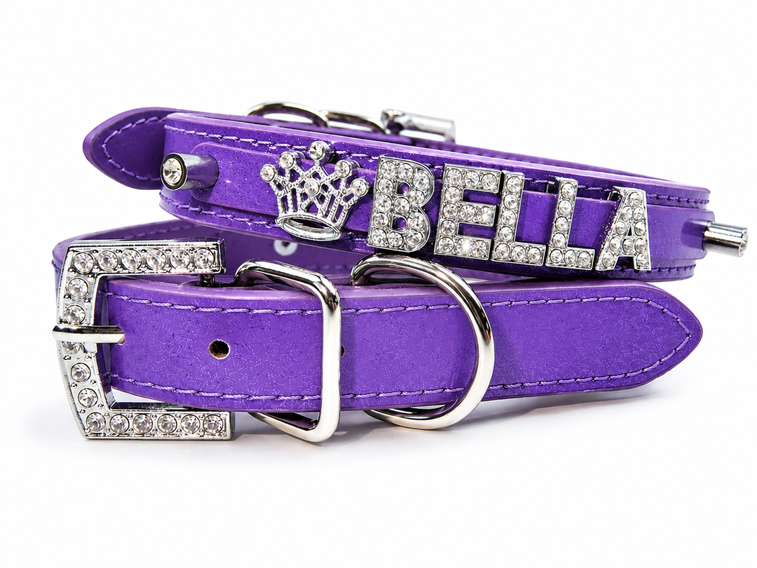 Purple faux-leather pet collar with silver-tone hardware, featuring a crown emblem and the name 'BELLA' embellished with rhinestones on a white background.